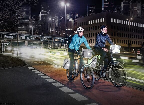Radfahren bei Dunkelheit Eine Frau und ein Mann fahren bei Dunkelheit in der Stadt mit dem Rad.